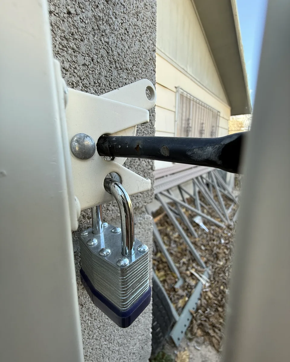 Close up of a padlock through the latch of a side gate, photographed on the way out.
