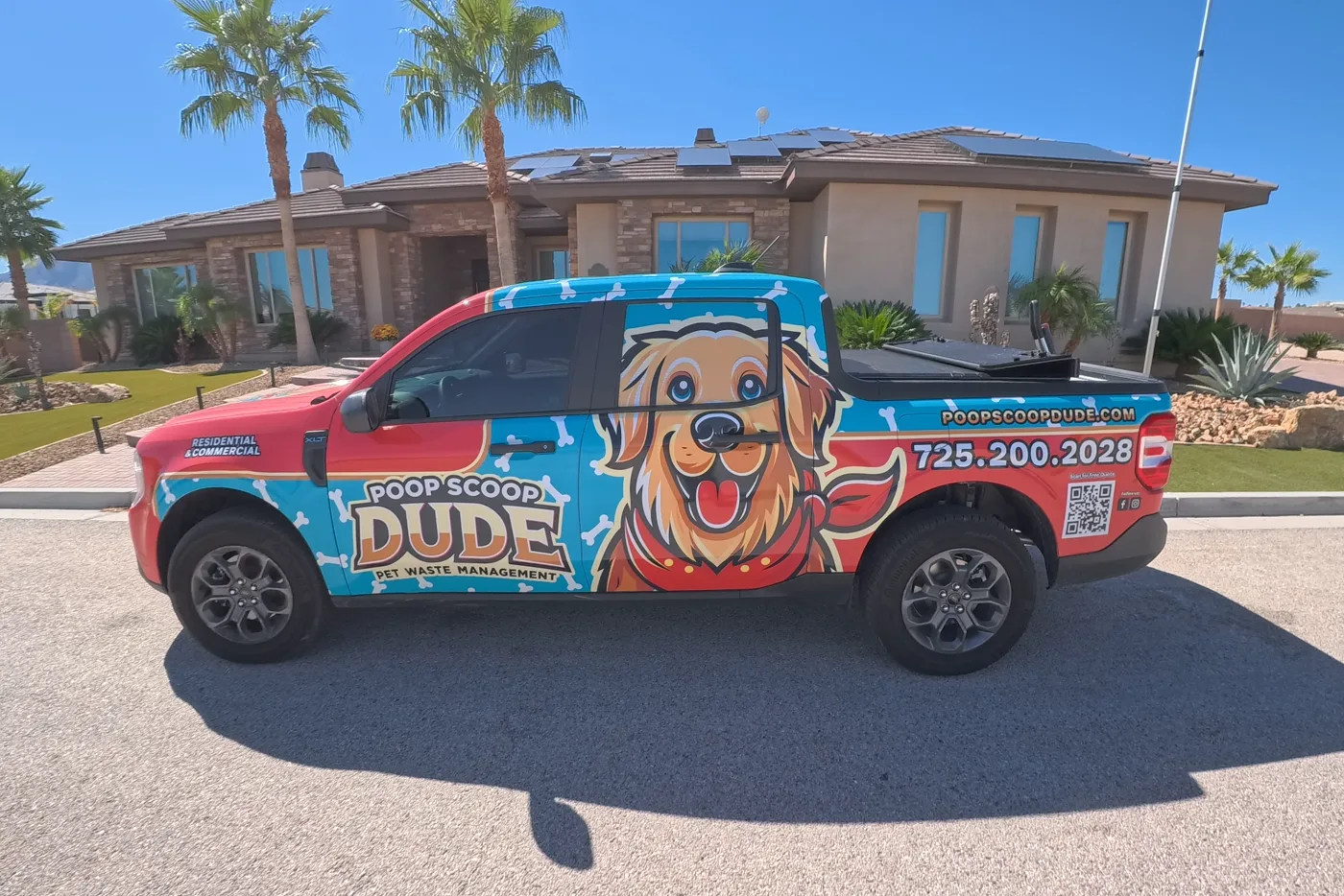 The wrapped Poop Scoop Dude truck parked at the curb of a Las Vegas home under palm trees.