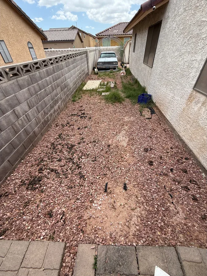 A long gravel side yard with waste scattered along it.